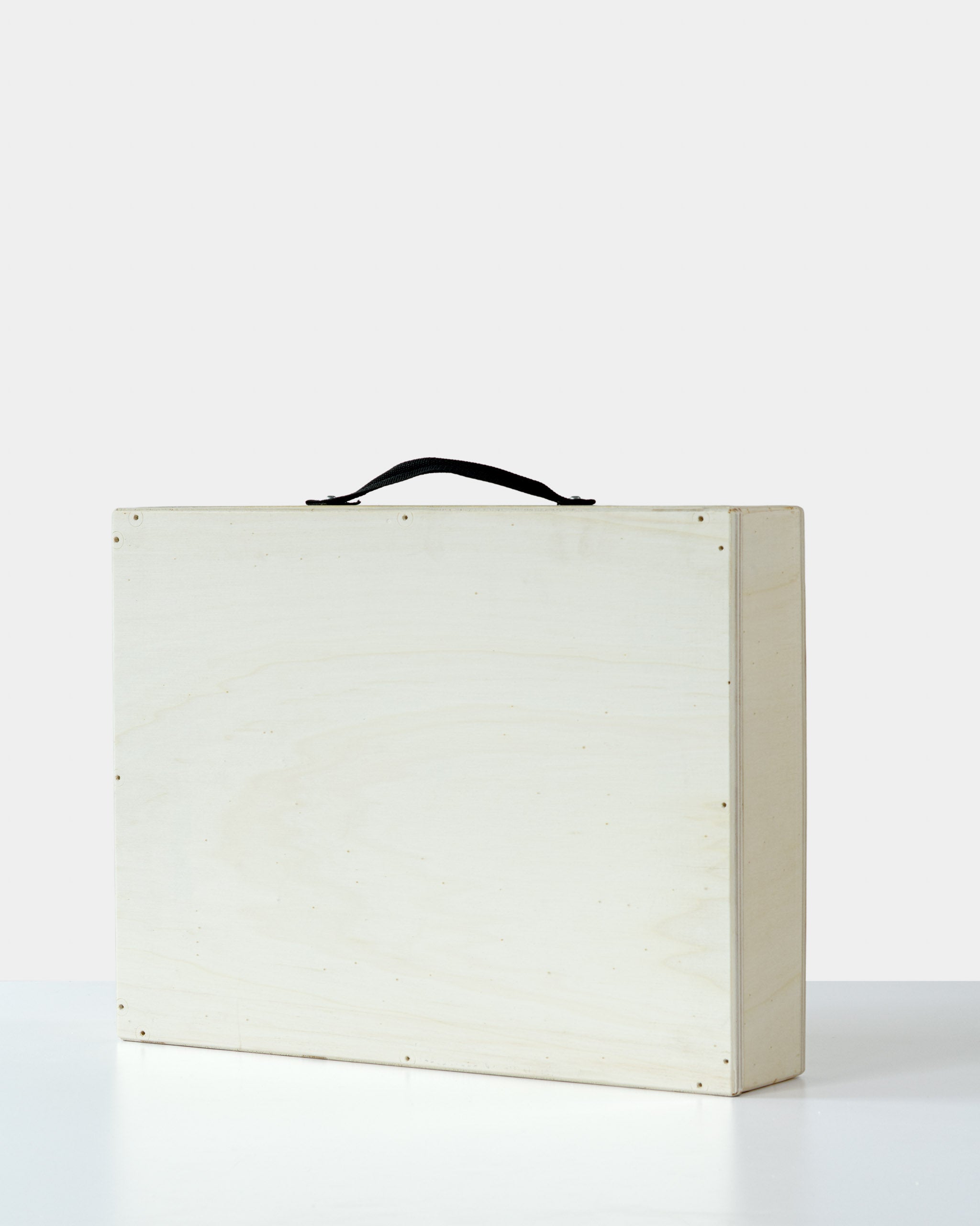 Minimalist wooden art crate with a black handle, closed and ready for safe artwork transportation or delivery.