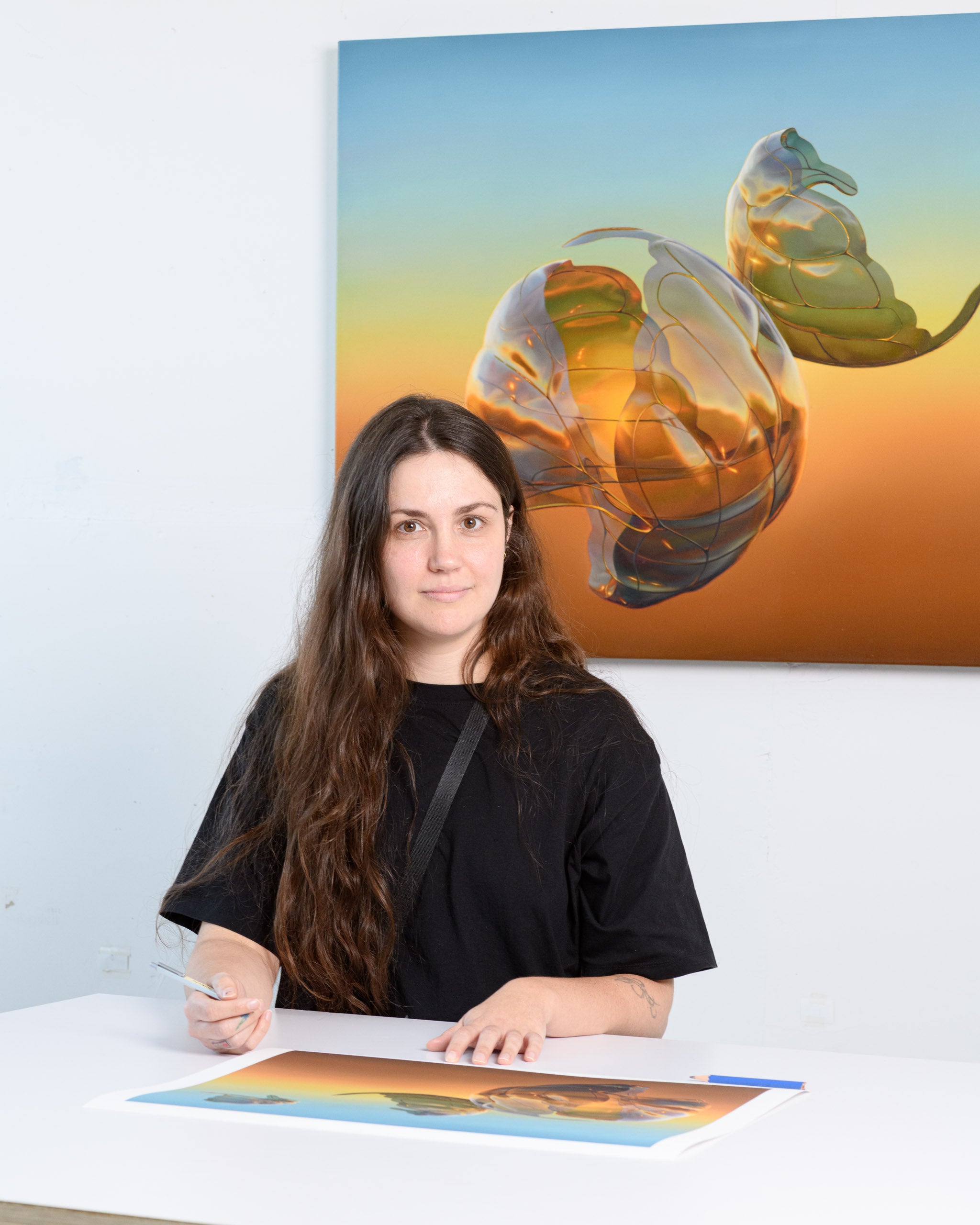 Woman sitting at a desk with a painting of a glass sculpture in the background