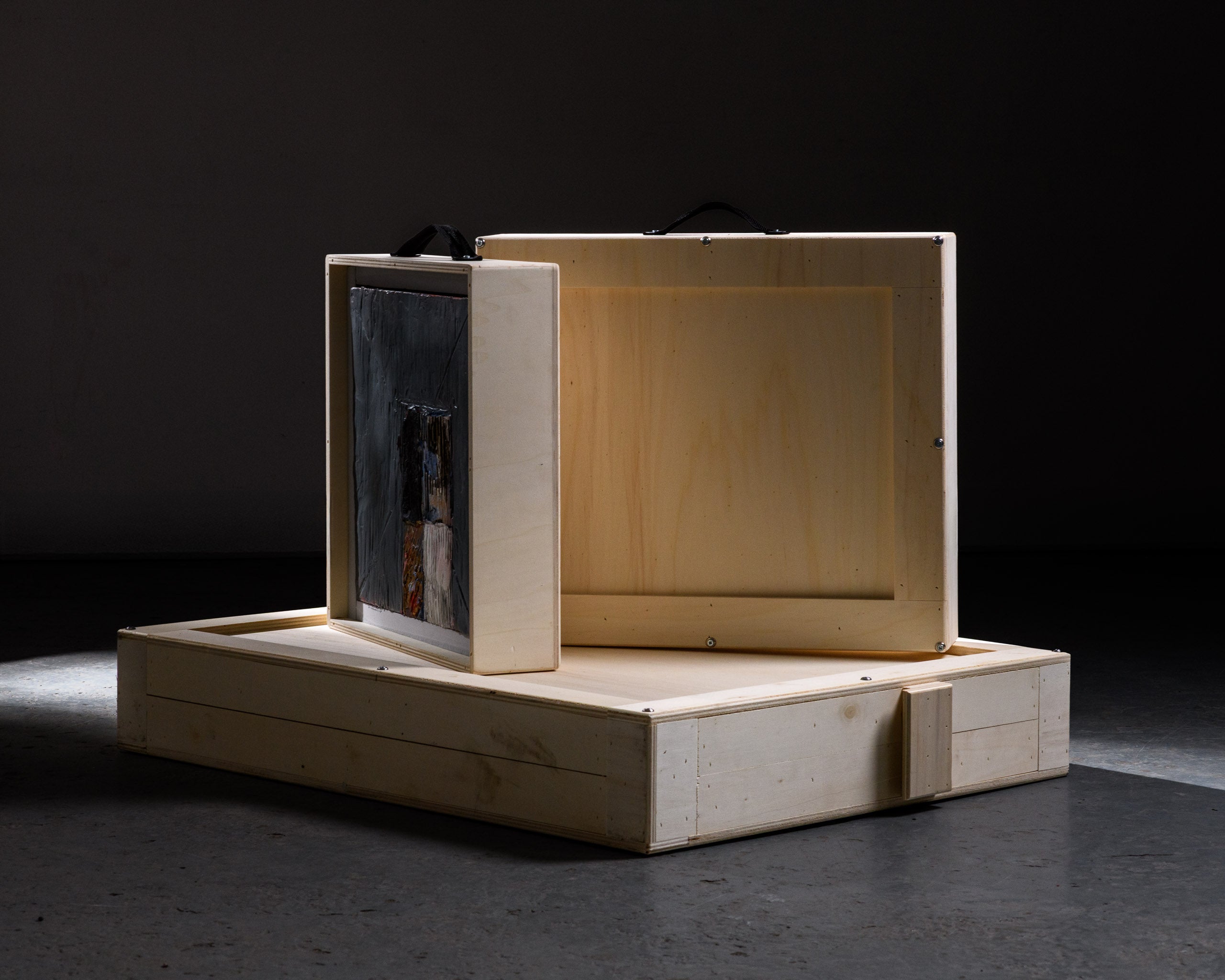 A secure art crate partially opened to reveal a framed painting inside, illustrating the internal foam protection and tailored fit designed for original artworks.