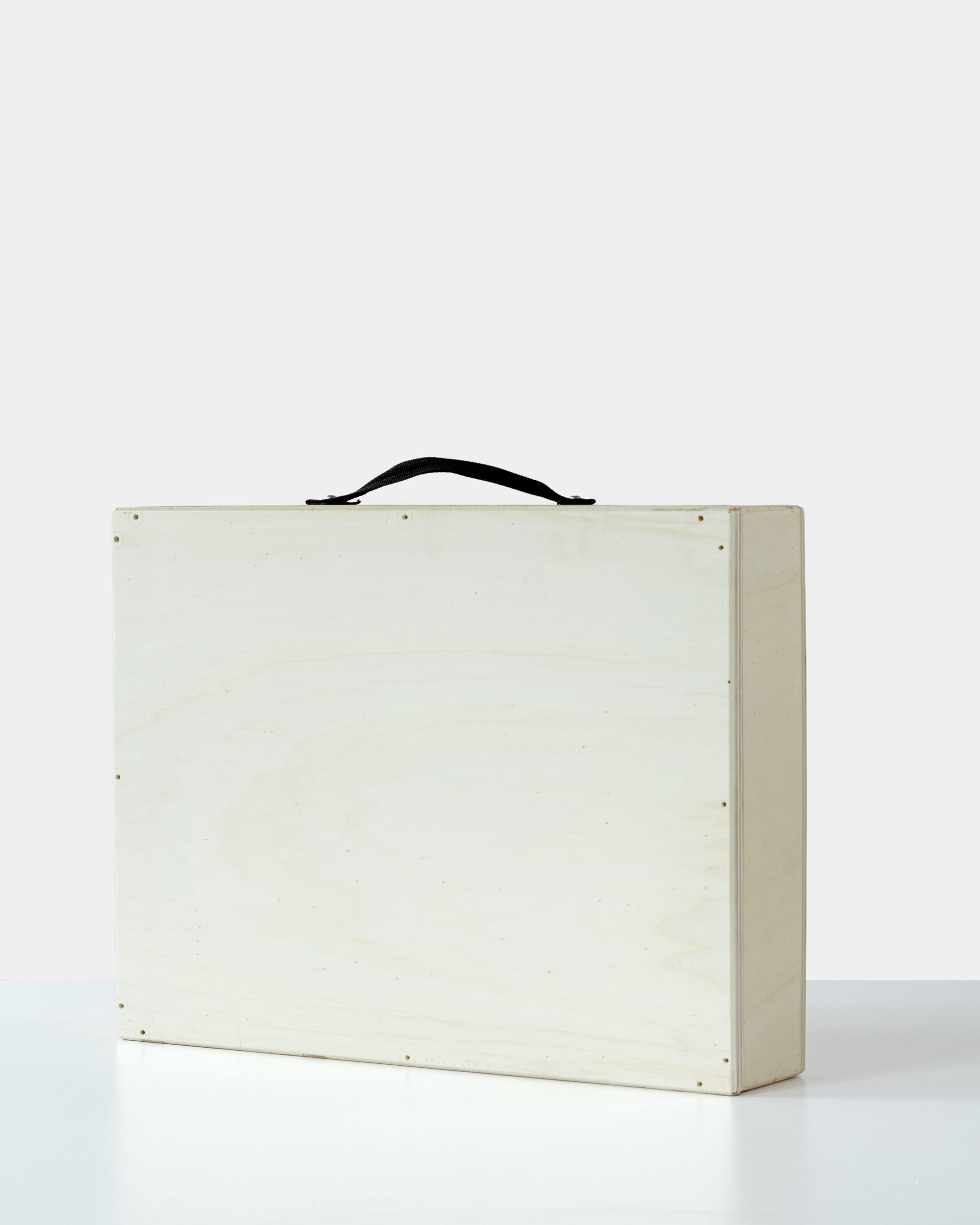 Minimalist wooden art crate with a black handle, closed and ready for safe artwork transportation or delivery.