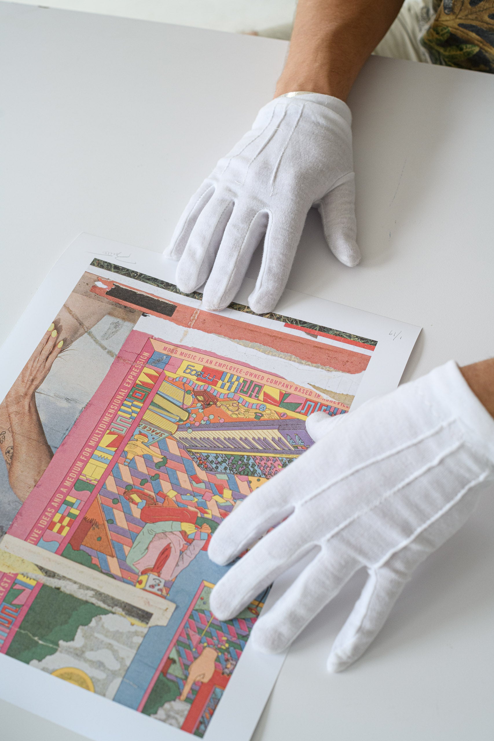 Gloved hands position a limited edition print flat on the table, highlighting the care and craftsmanship of GEMS print handling.