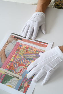 Gloved hands position a limited edition print flat on the table, highlighting the care and craftsmanship of GEMS print handling.