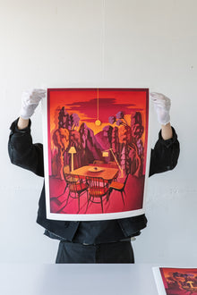 Artist holding Print artwork of a stylized dining room with red and orange tones.