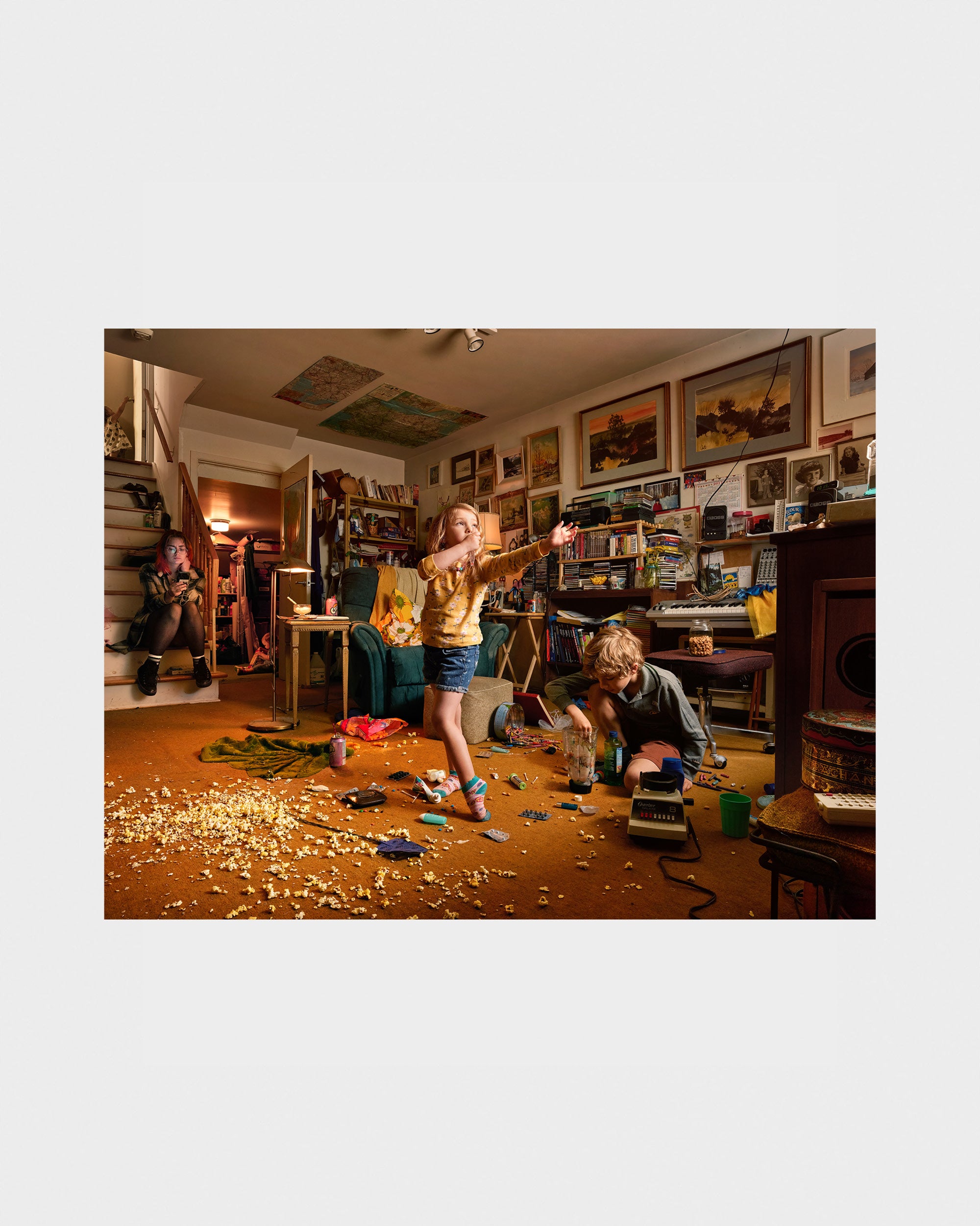 Photograph of Two children playing in a cluttered room with toys and furniture.